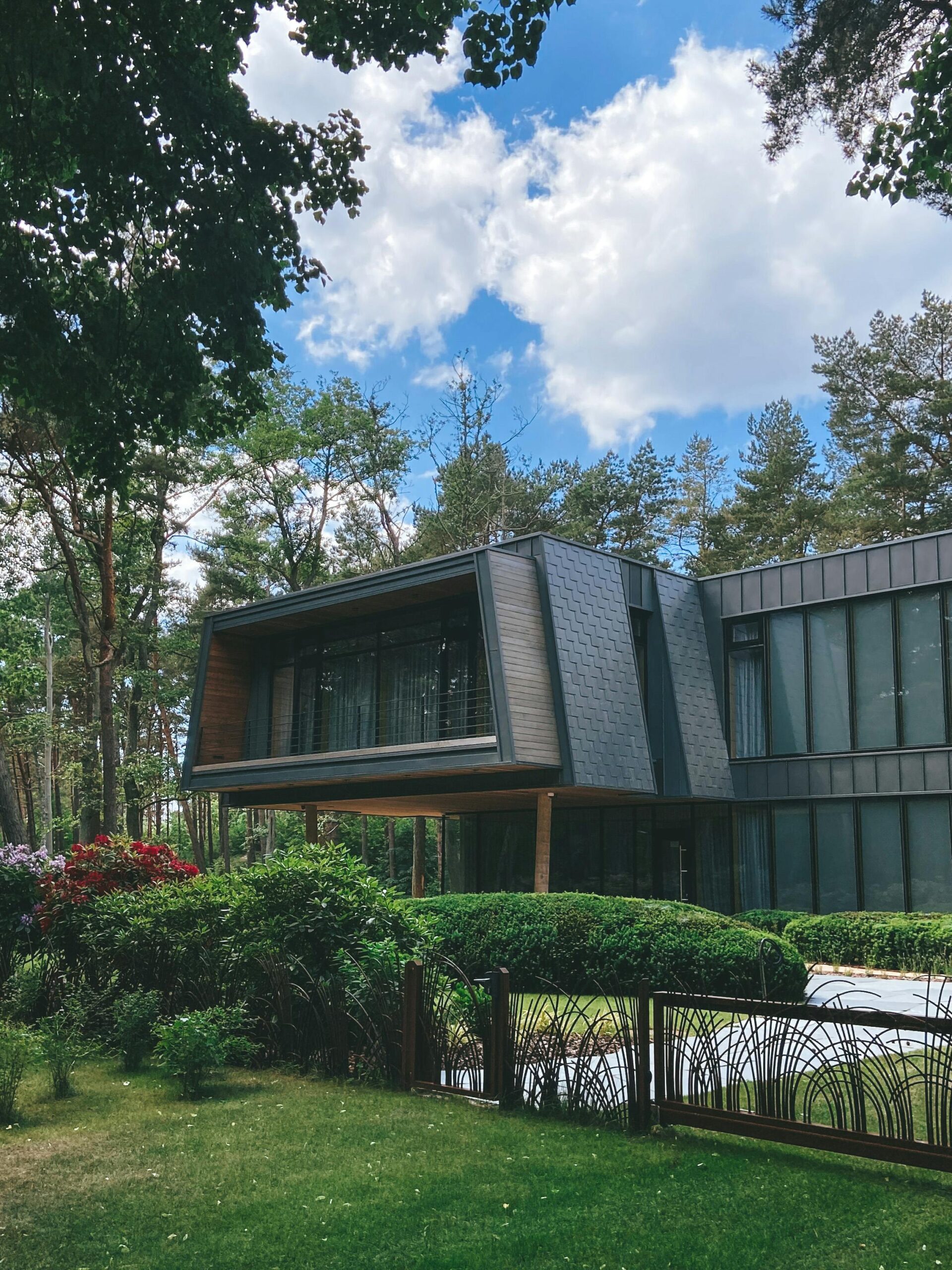 Nos biens Contemporary luxury house exterior surrounded by lush garden on a sunny day.