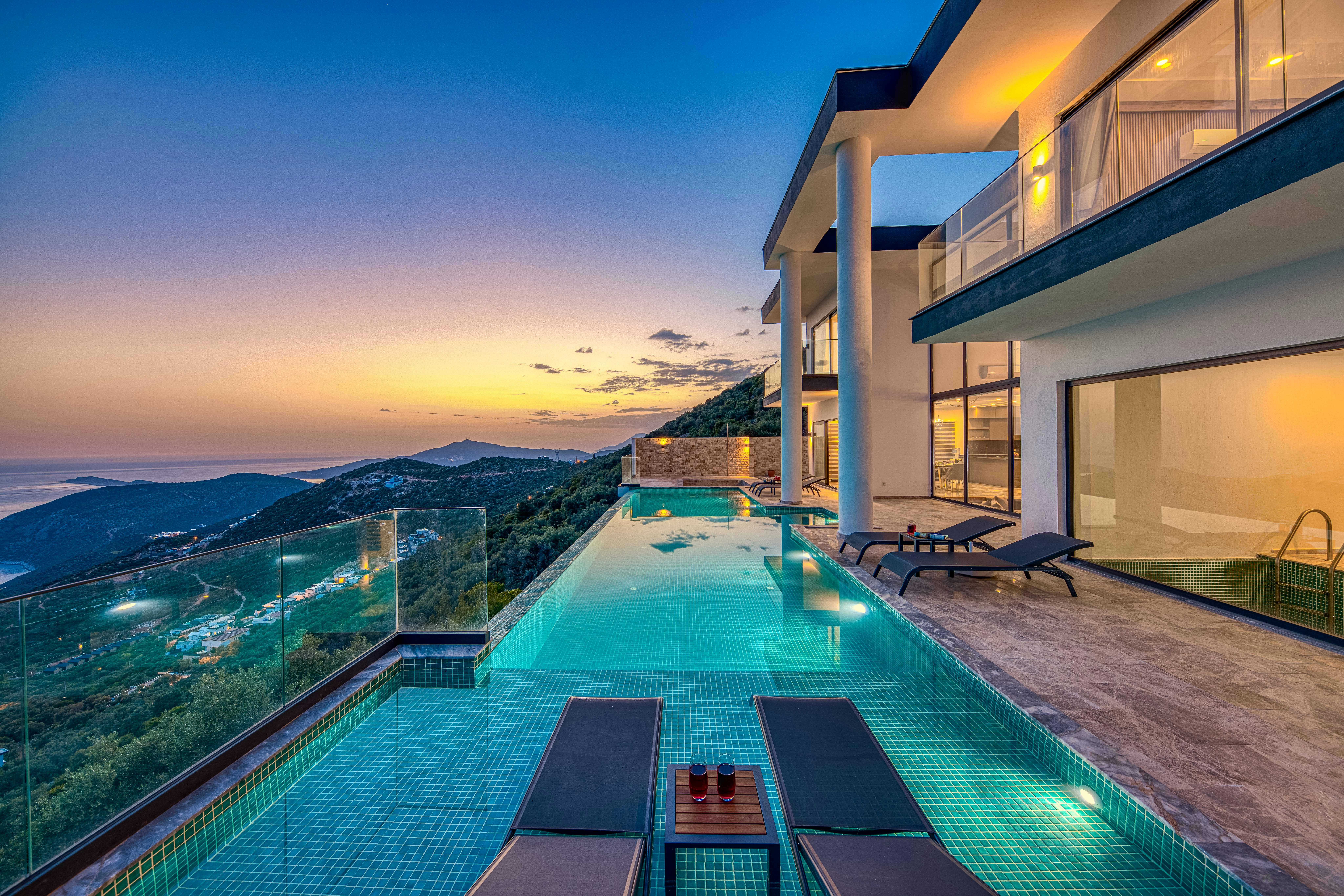 Nos biens Stunning luxury villa overlooking the ocean with an infinity pool at sunset.