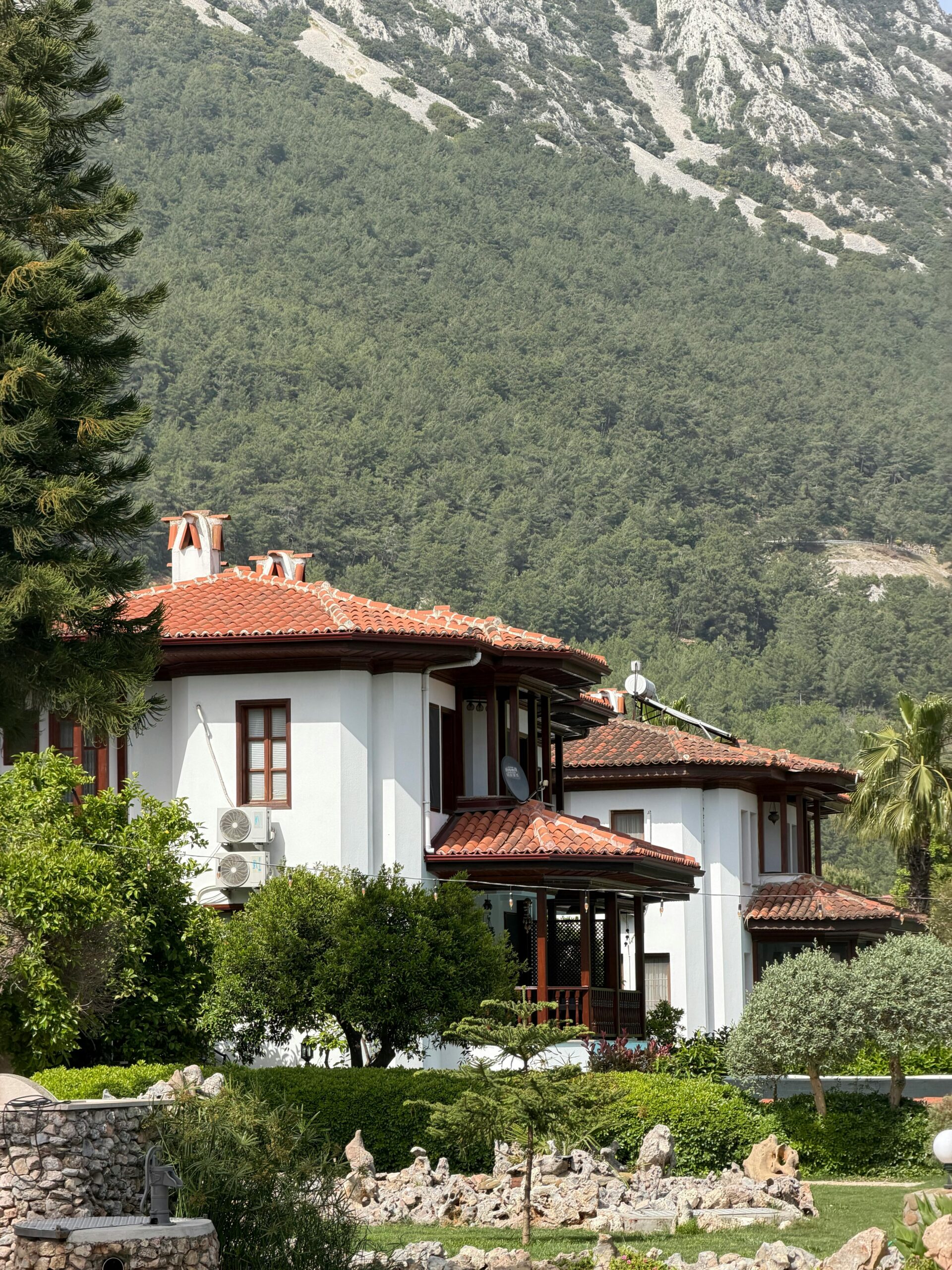 Nos biens Charming white house with red roofs surrounded by lush vegetation and mountains in Muğla, Turkey.