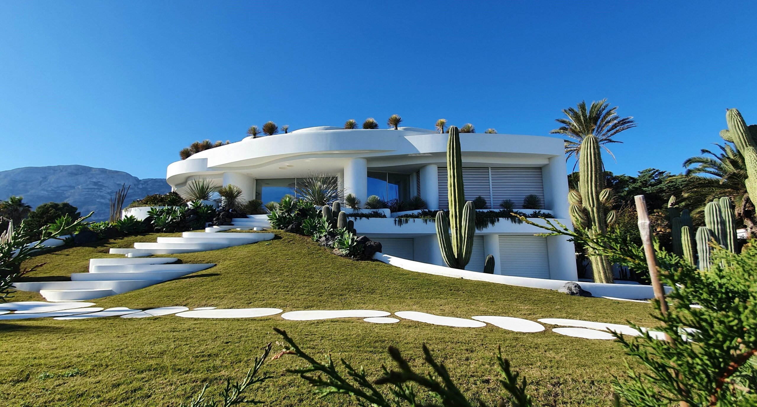 Nos biens Contemporary white villa with garden and cacti in Dénia, Spain under a clear blue sky.