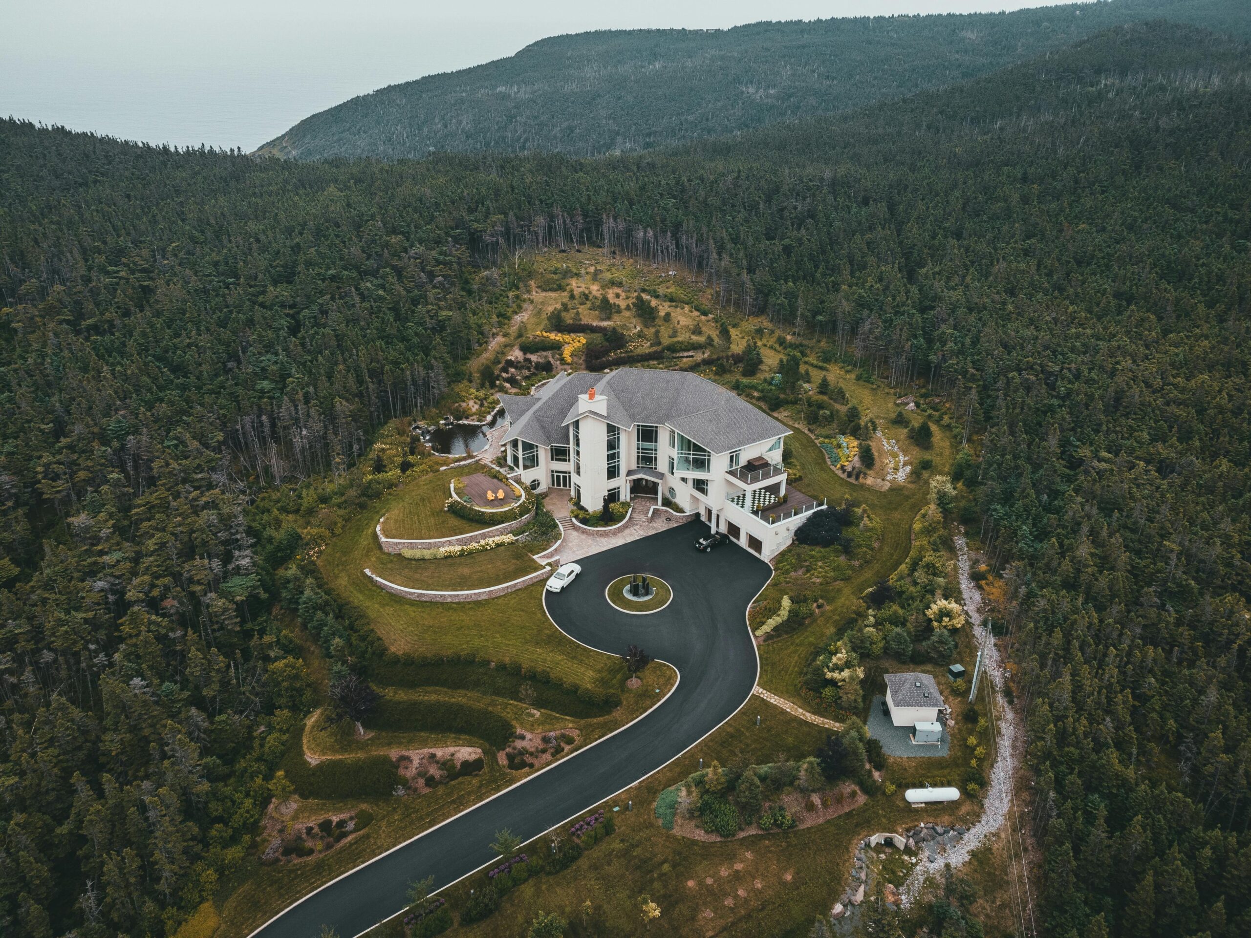 Nos biens A stunning aerial view of a luxurious mansion surrounded by lush greenery and scenic countryside.
